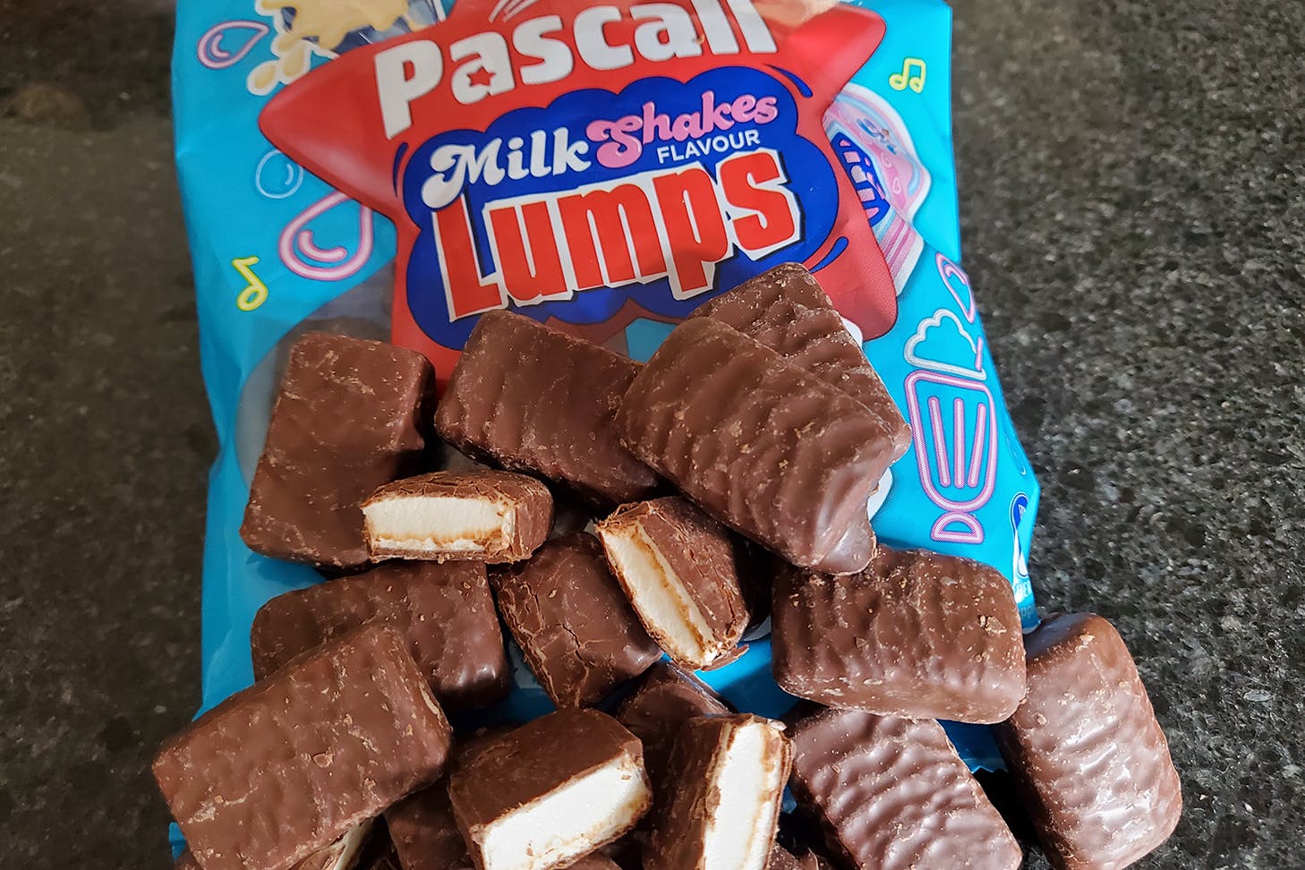 A torn open packet of milkshakes lumps spills onto the table.